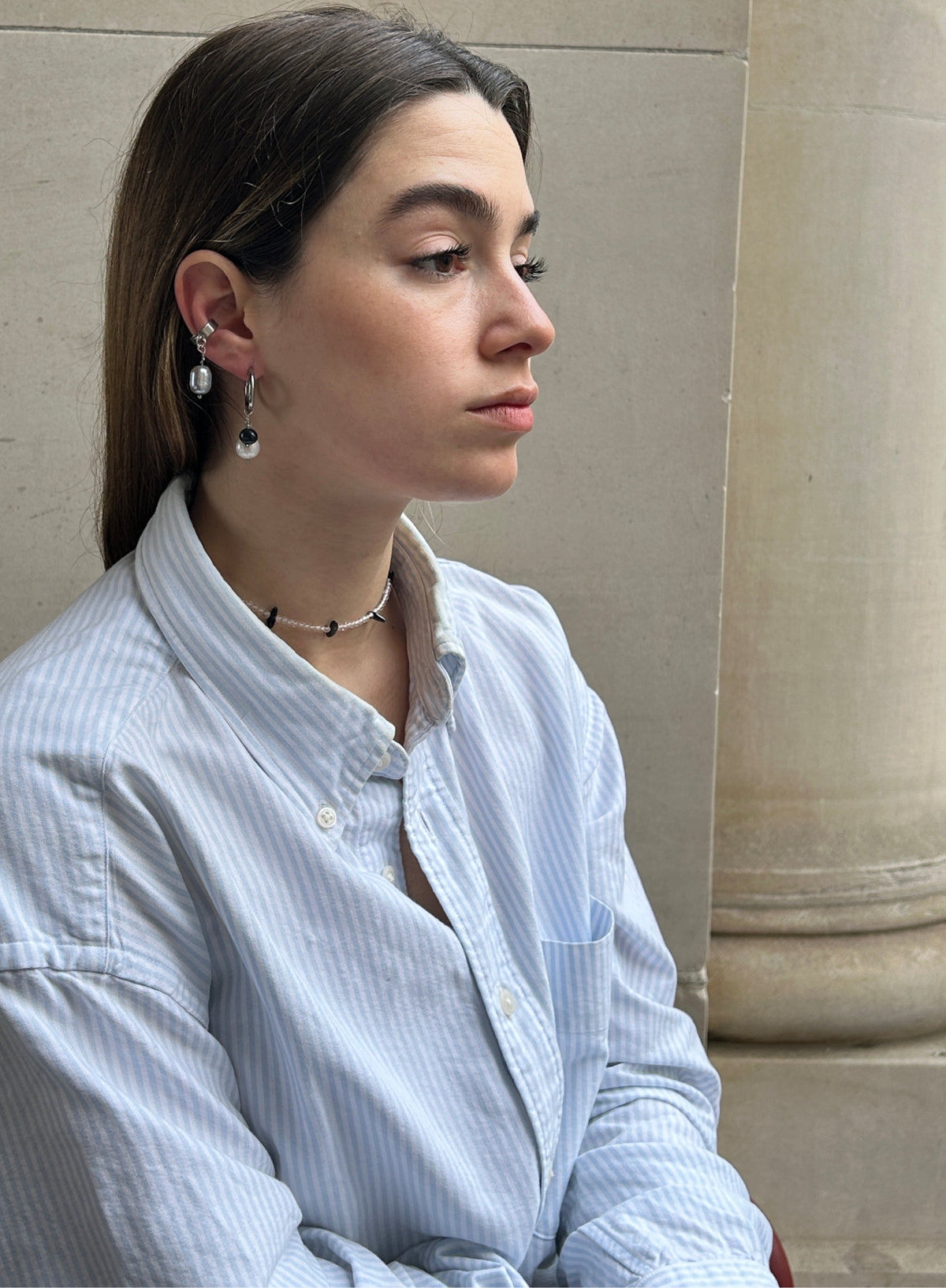 woman in blue stripe shirt wearing pearl earrings and beaded necklace