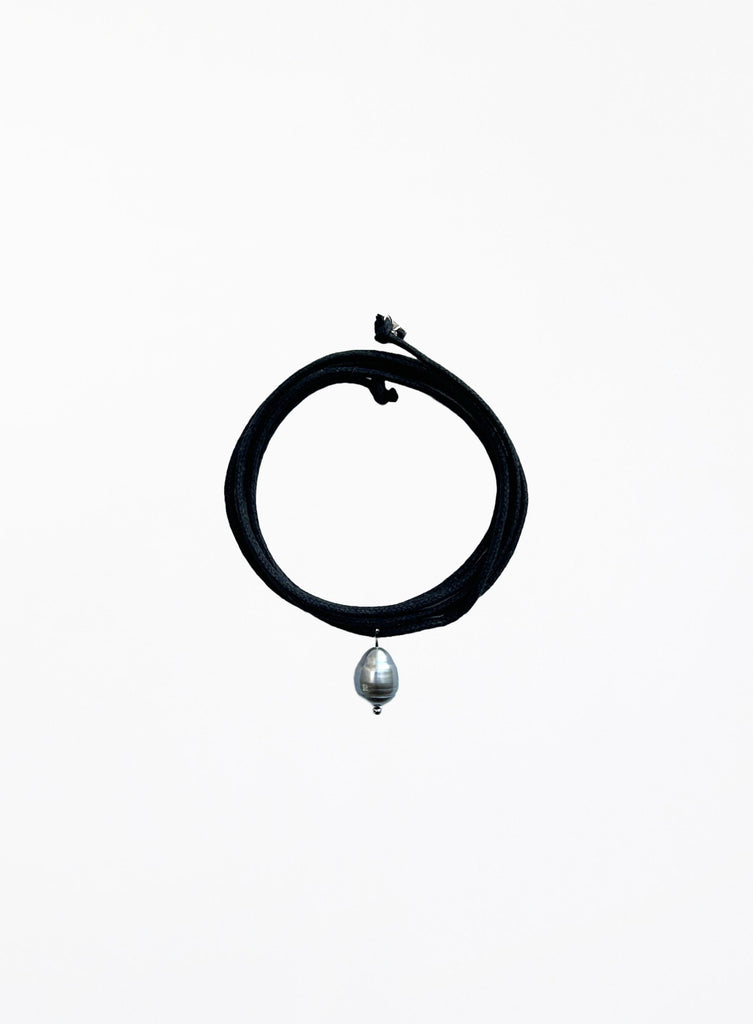 Black choker necklace with a pearl pendant on a white background