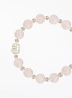 Bracelet with rose quartz beads and solo pearl on a white background