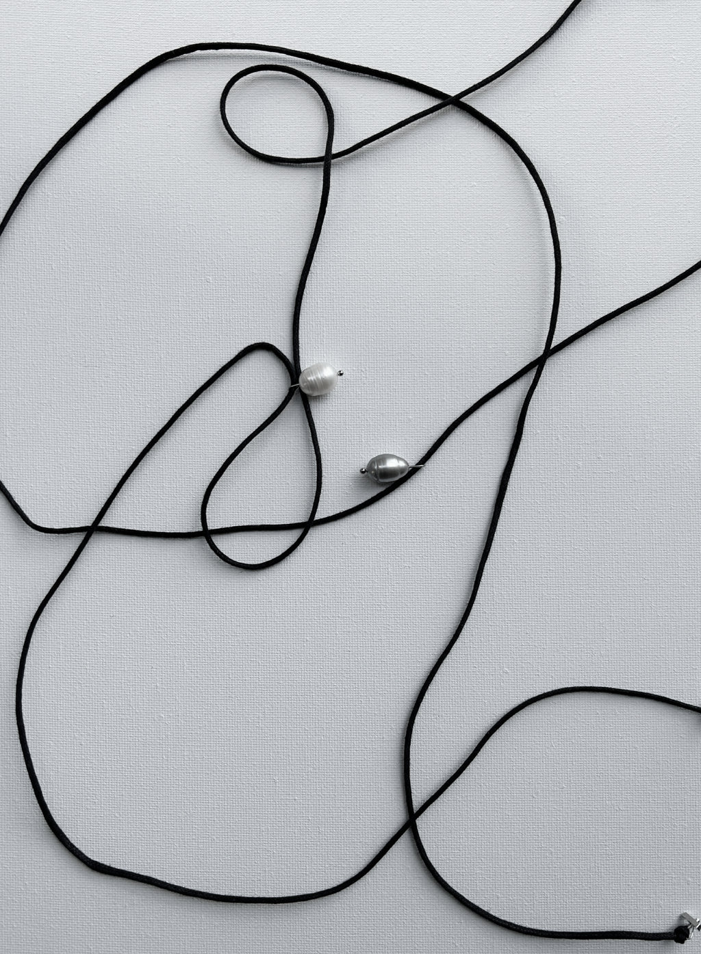 Black cord with pearl pendants on a light gray background