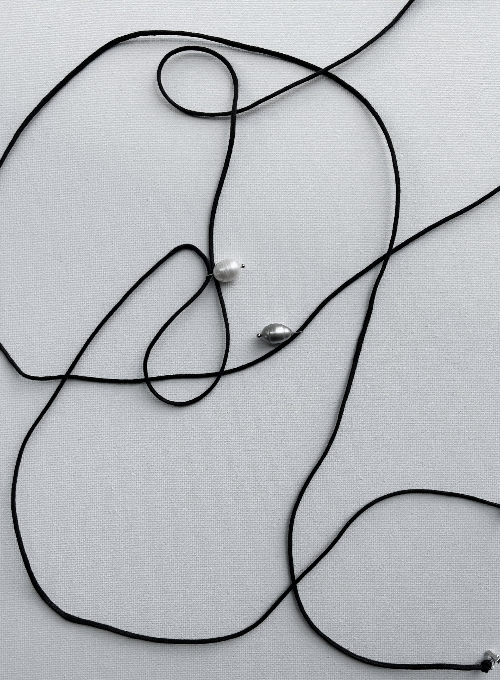 Black cord with pearl pendants on a light gray background
