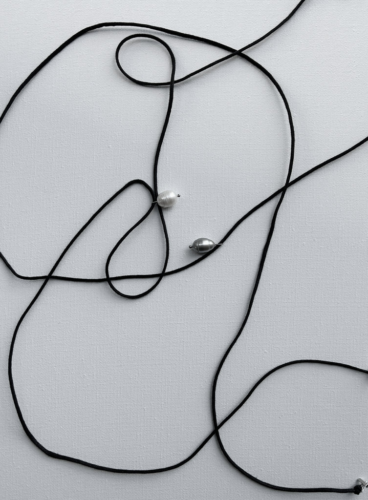 Black cord with pearl pendants on a light gray background