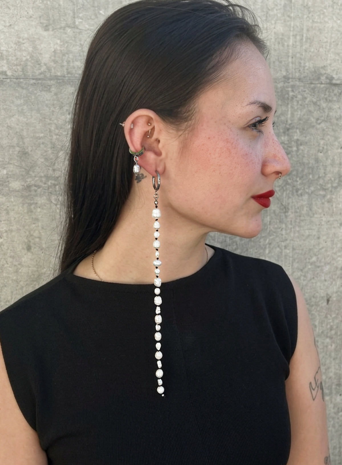 woman in red lips and black dress wearing a long shoulder duster pearl earrings