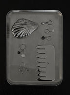 flatlay shot of stainless steel comb massager and multiple earrings with pearls and ear cuffs. also a shell pocket mirror