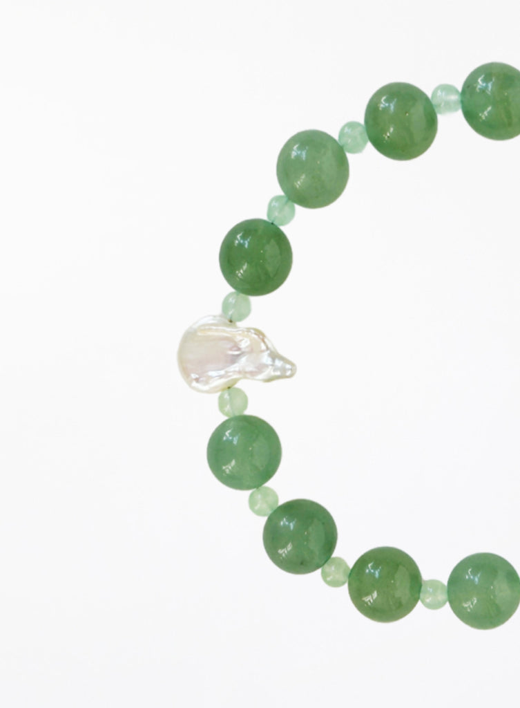 Green beaded bracelet with pearl on a white background