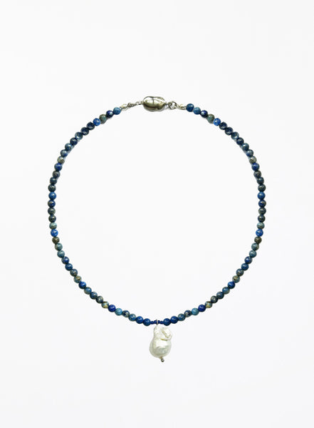 Necklace with blue beads and a white baroque pearl pendant on a white background