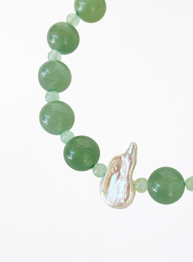 Green beaded bracelet with pearl on a white background