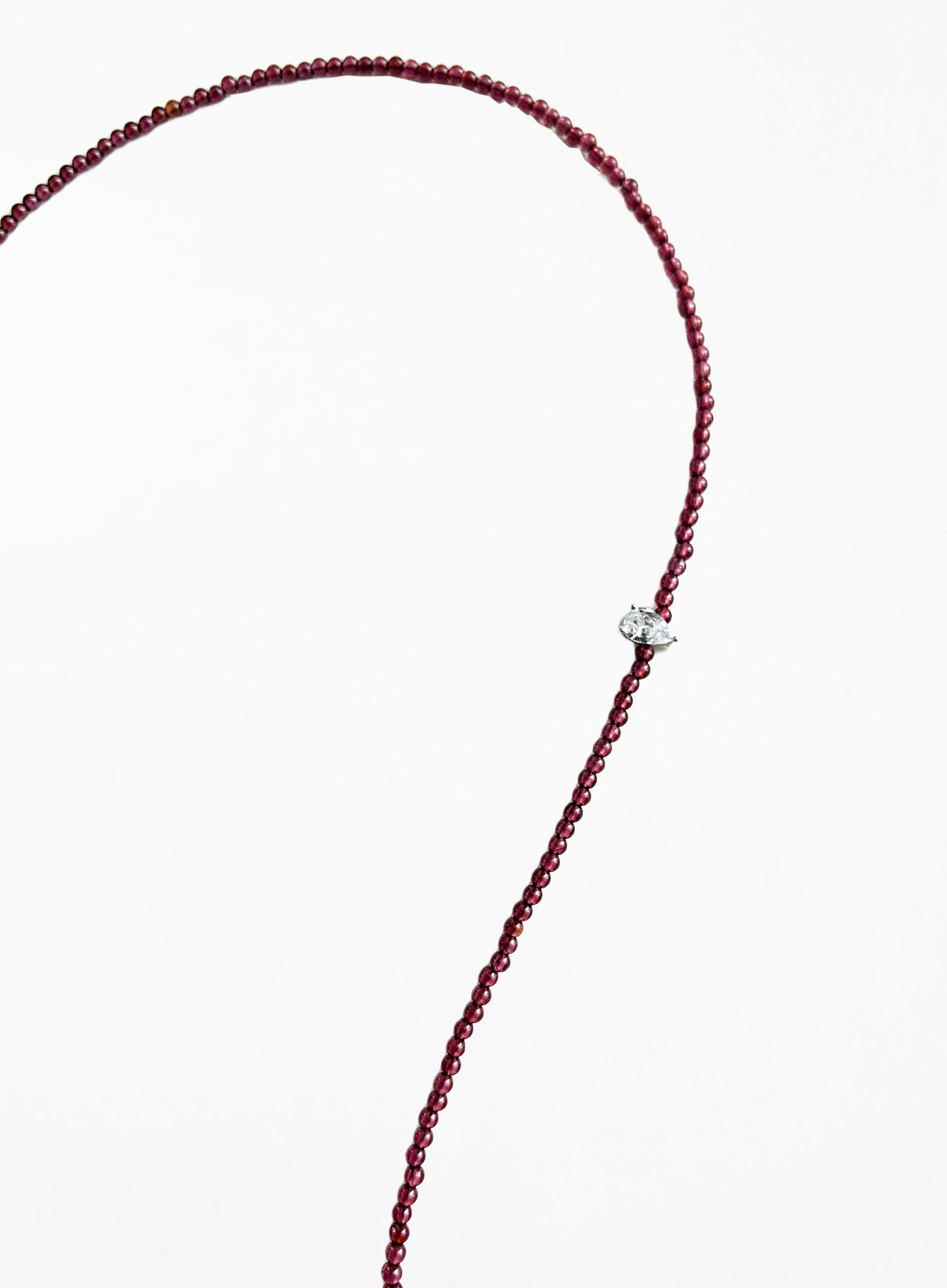 Thin garnet beaded necklace with tear drop charm on a white background