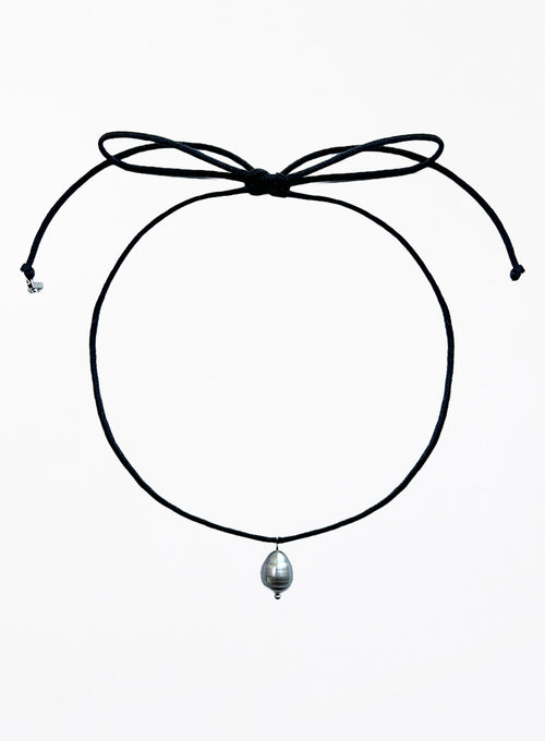 Thin black choker necklace with a pearl pendant on a white background