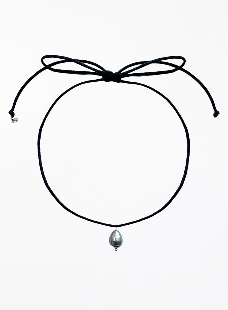 Thin black choker necklace with a pearl pendant on a white background