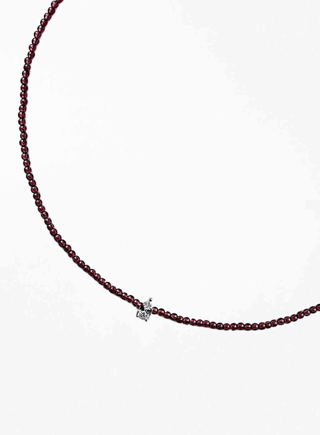 Thin garnet beaded necklace with tear drop charm on a white background