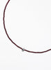 Thin garnet beaded necklace with tear drop charm on a white background