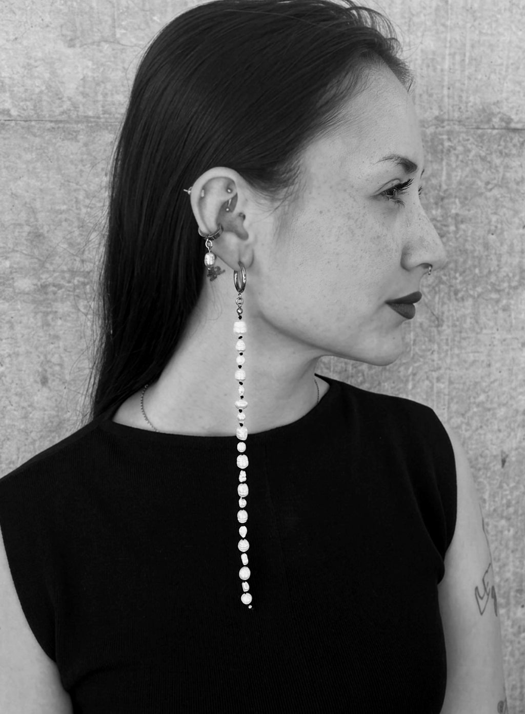 black and white photo of a woman wearing a long pearl earrings