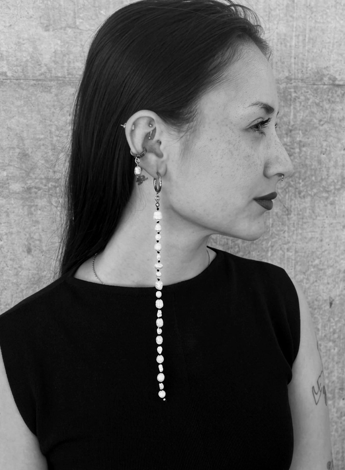 black and white photo of a woman wearing a long pearl earrings