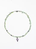 A beaded necklace made of small light green and pale blue gemstone chips, with a central pumpkin shaped lavender bead and a silver clasp, shown on a plain white background.