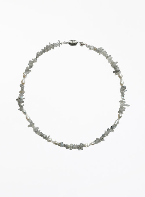 A delicate necklace made of small, irregular gray stone chips and white pearl beads, arranged in a circle on a plain white background.