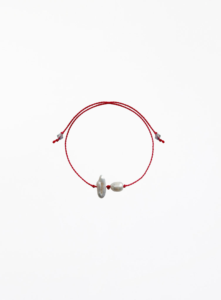 Red cord bracelet with two pearls on a white background