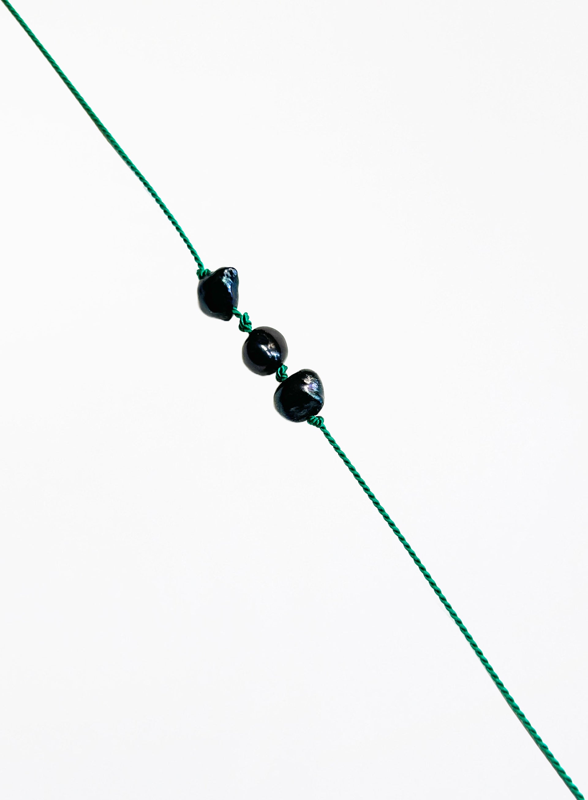 Green bracelet with black pearls on a white background
