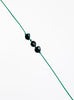 Green bracelet with black pearls on a white background