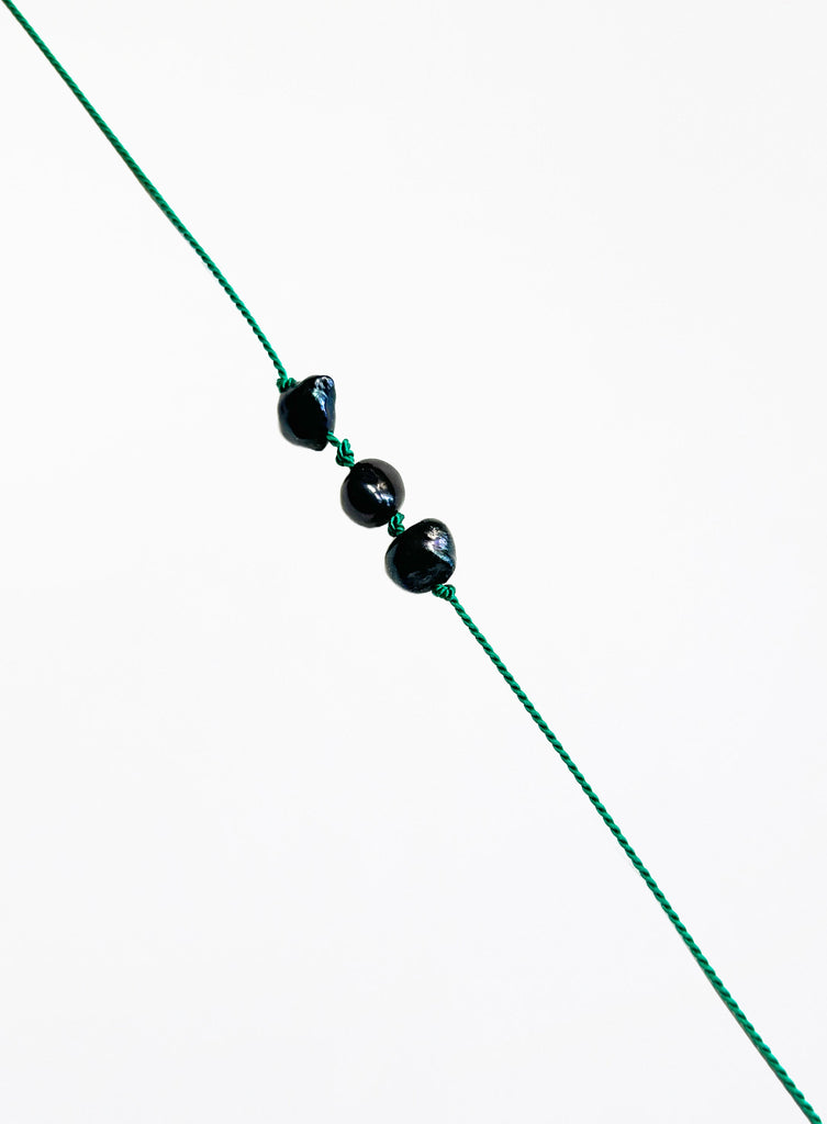 Green bracelet with black pearls on a white background