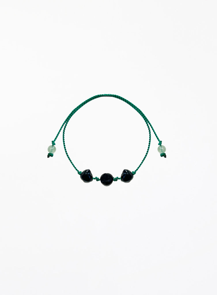 Green bracelet with black pearls on a white background