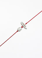 Red string with two pearls on a white background
