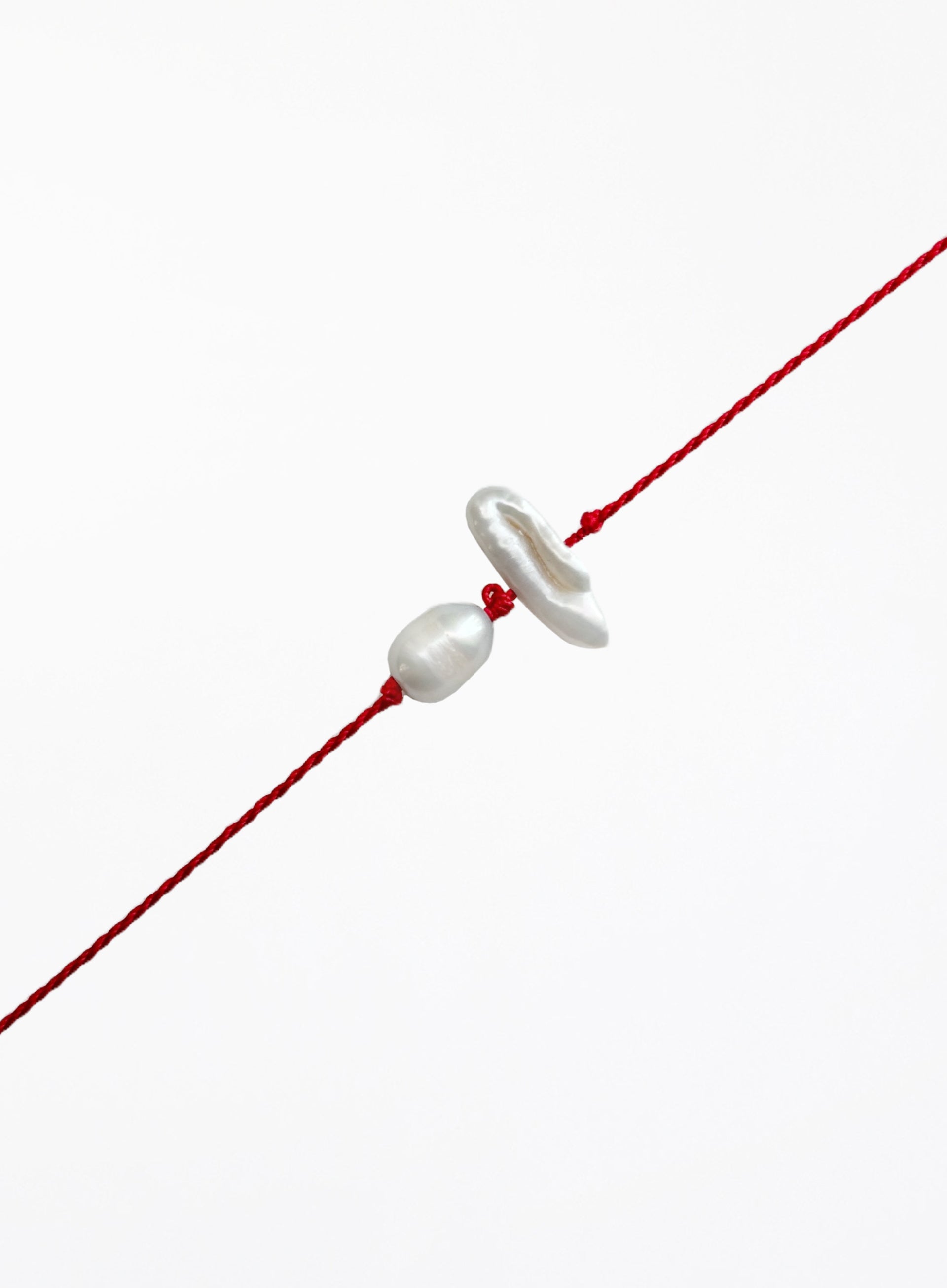 Red string with two pearls on a white background