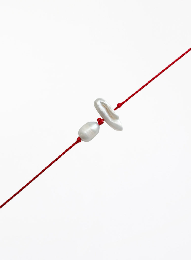 Red string with two pearls on a white background