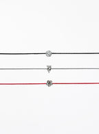 Three thin bracelets with different pendants on a white background