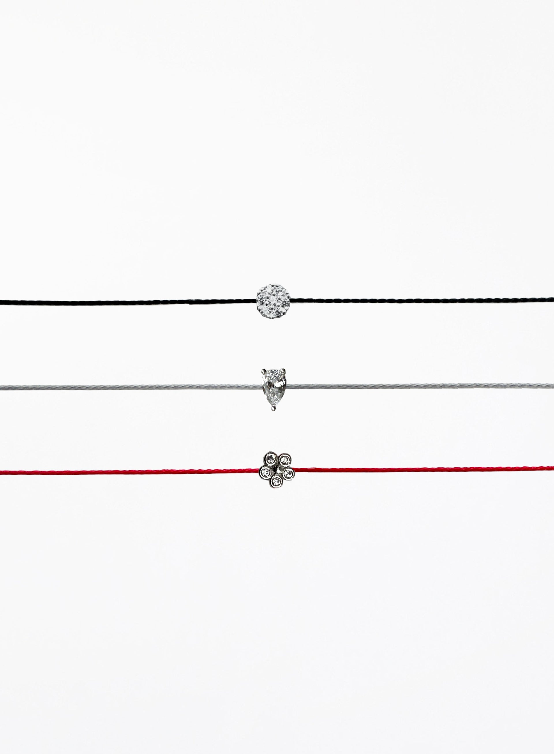 Three thin bracelets with different pendants on a white background