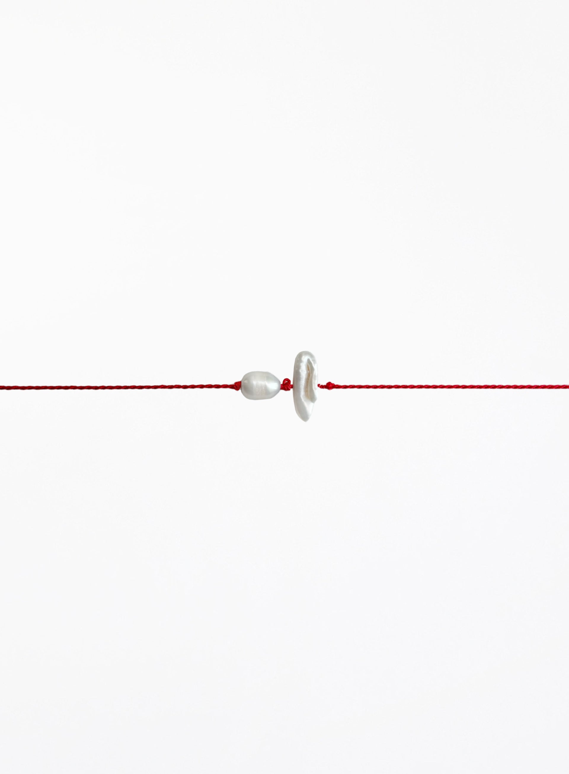 Red string with two pearls on a white background