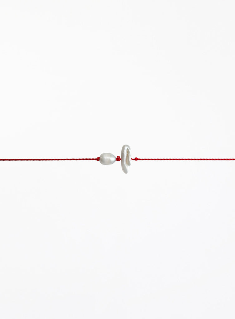 Red string with two pearls on a white background