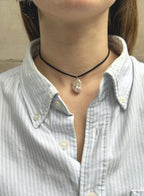 woman in stripe blue shirt wearing a cord necklace with a baroque pearl charm 