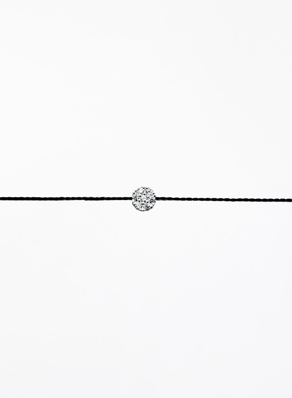 Black cord bracelet with a small round silver charm on a white background
