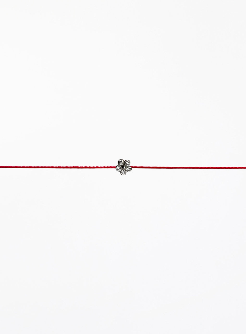 Red string bracelet with a small flower charm on a white background