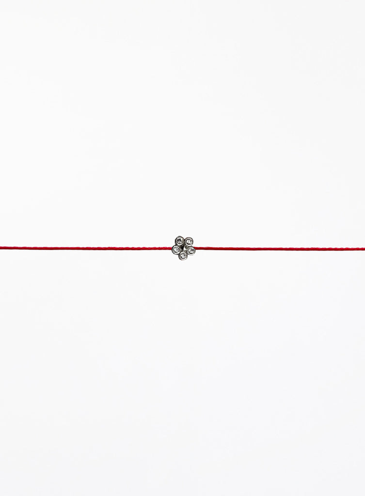 Red string bracelet with a small flower charm on a white background