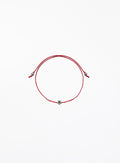 Red string bracelet with a small flower charm on a white background