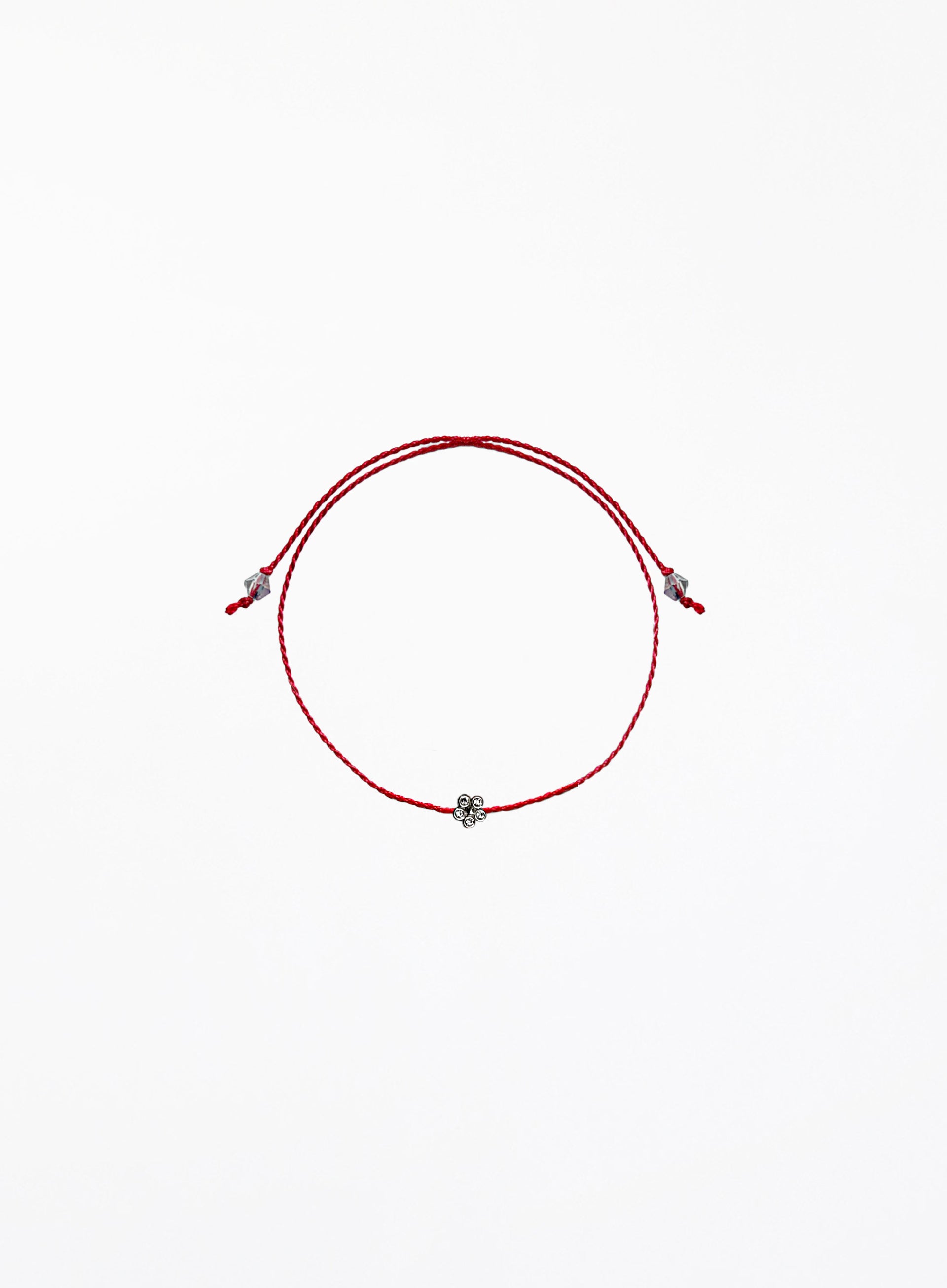 Red string bracelet with a small flower charm on a white background