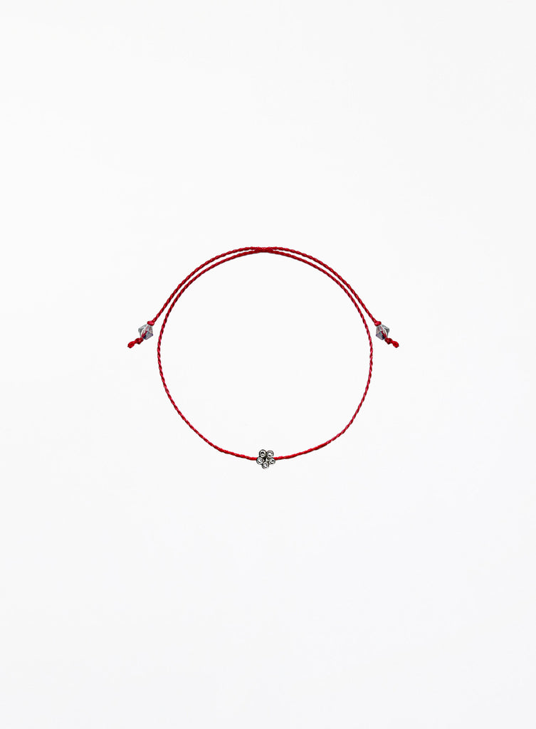 Red string bracelet with a small flower charm on a white background