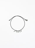 Black cord bracelet with small clear quartz charms on a white background