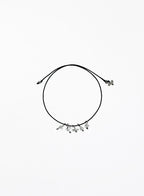 Black cord bracelet with small clear quartz charms on a white background