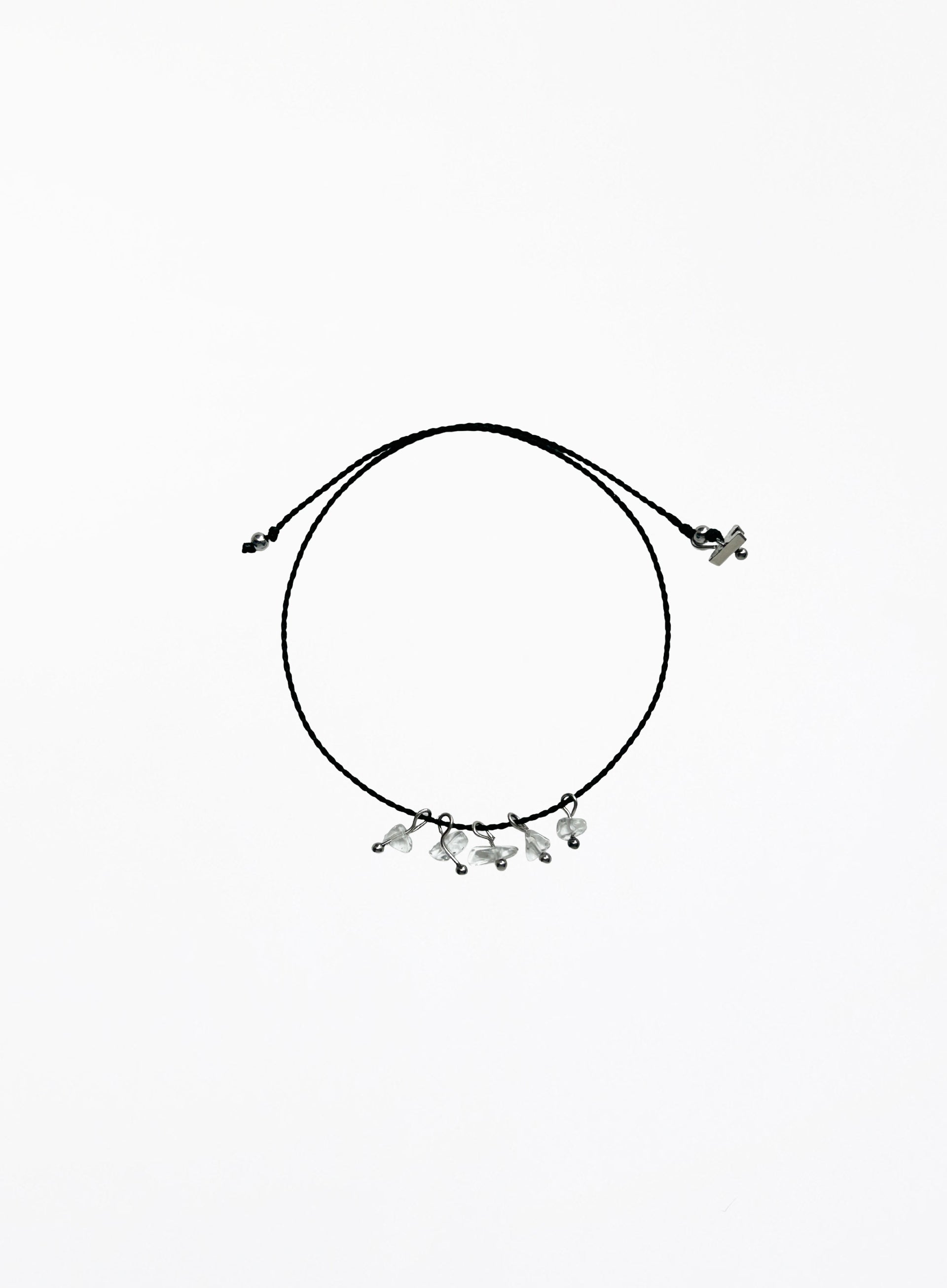 Black cord bracelet with small clear quartz charms on a white background