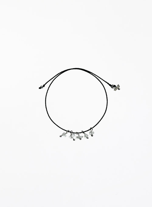 Black cord bracelet with small clear quartz charms on a white background