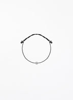 Black bracelet with a small round charm on a white background