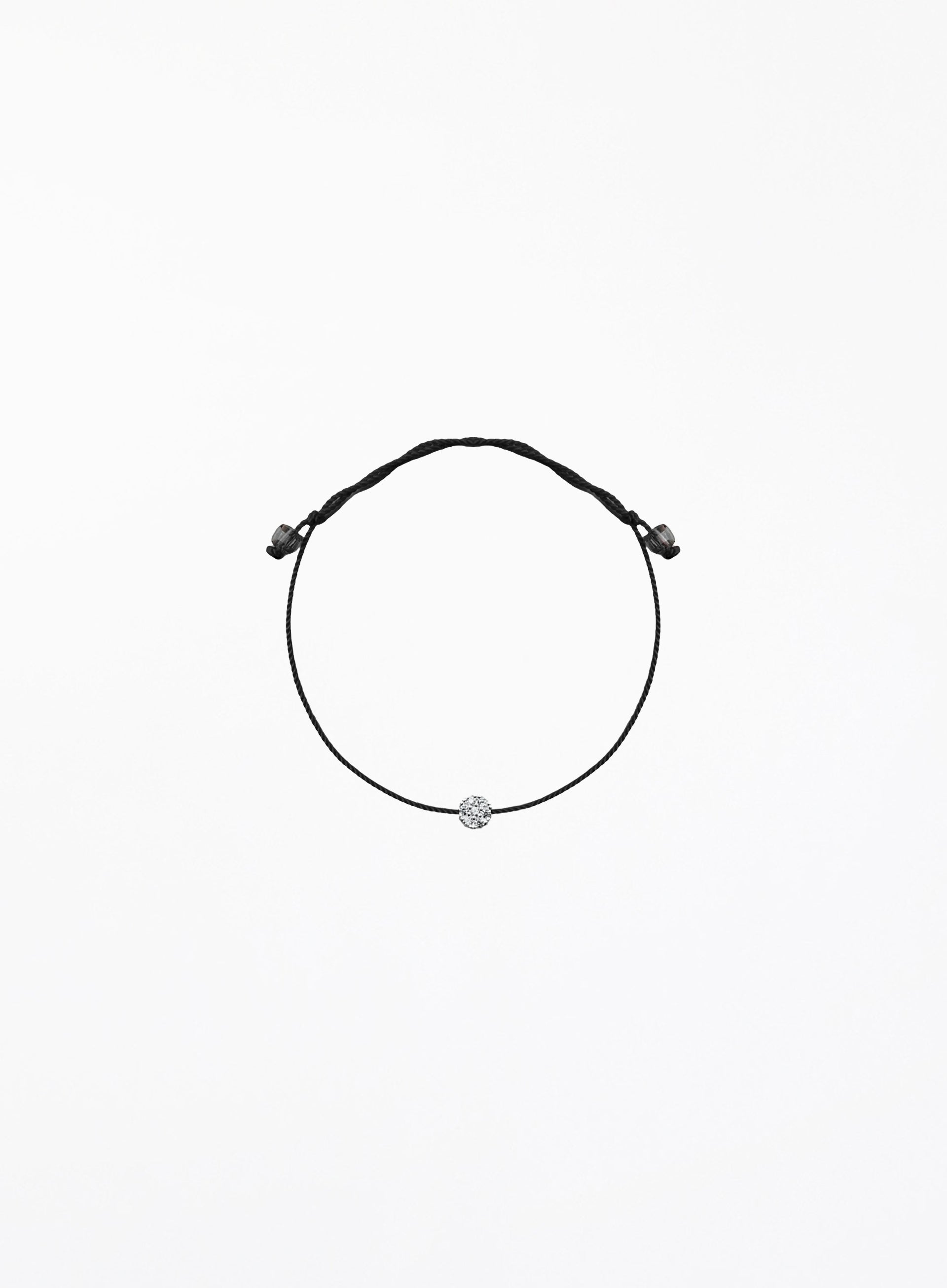 Black bracelet with a small round charm on a white background