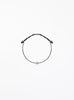 Black bracelet with a small round charm on a white background