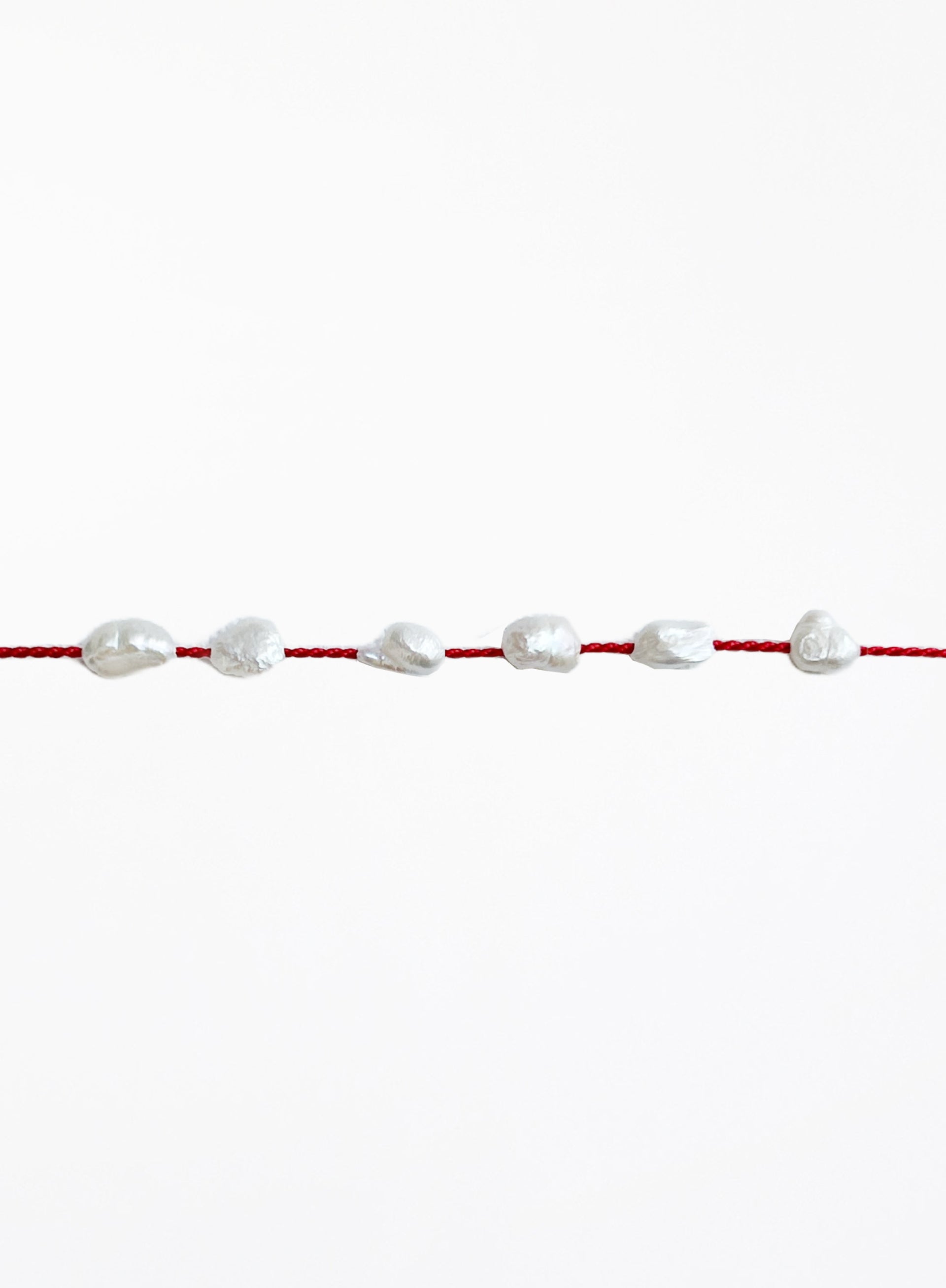 Red bracelet with pearls on a white background