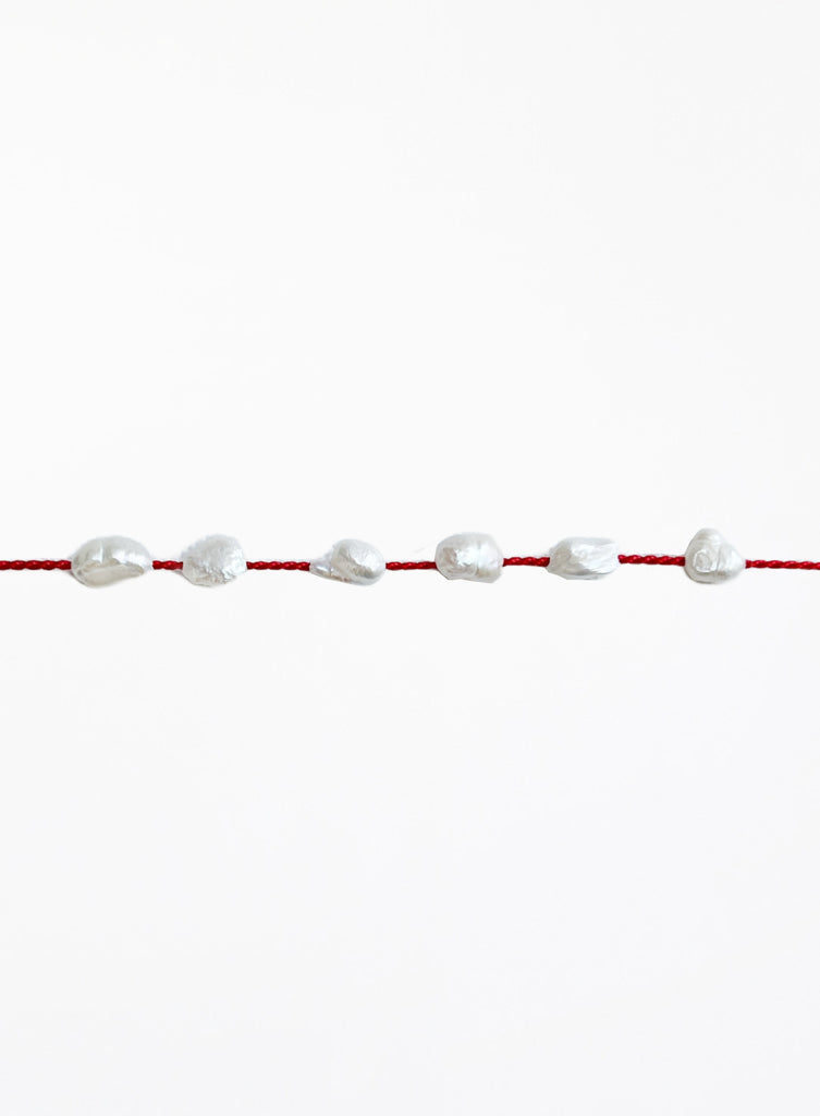 Red bracelet with pearls on a white background