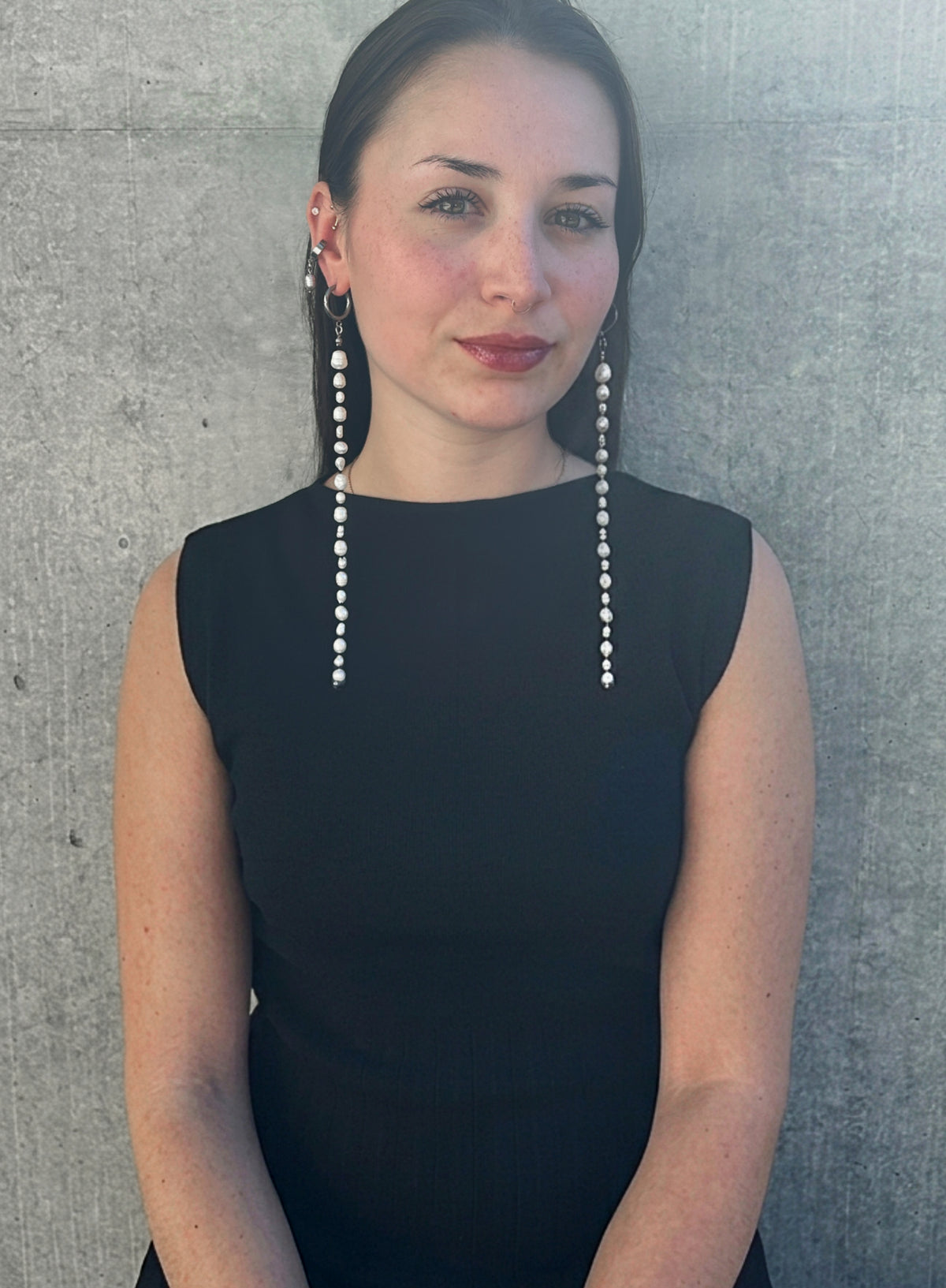woman in black dress wearing a long shoulder duster pearl earrings