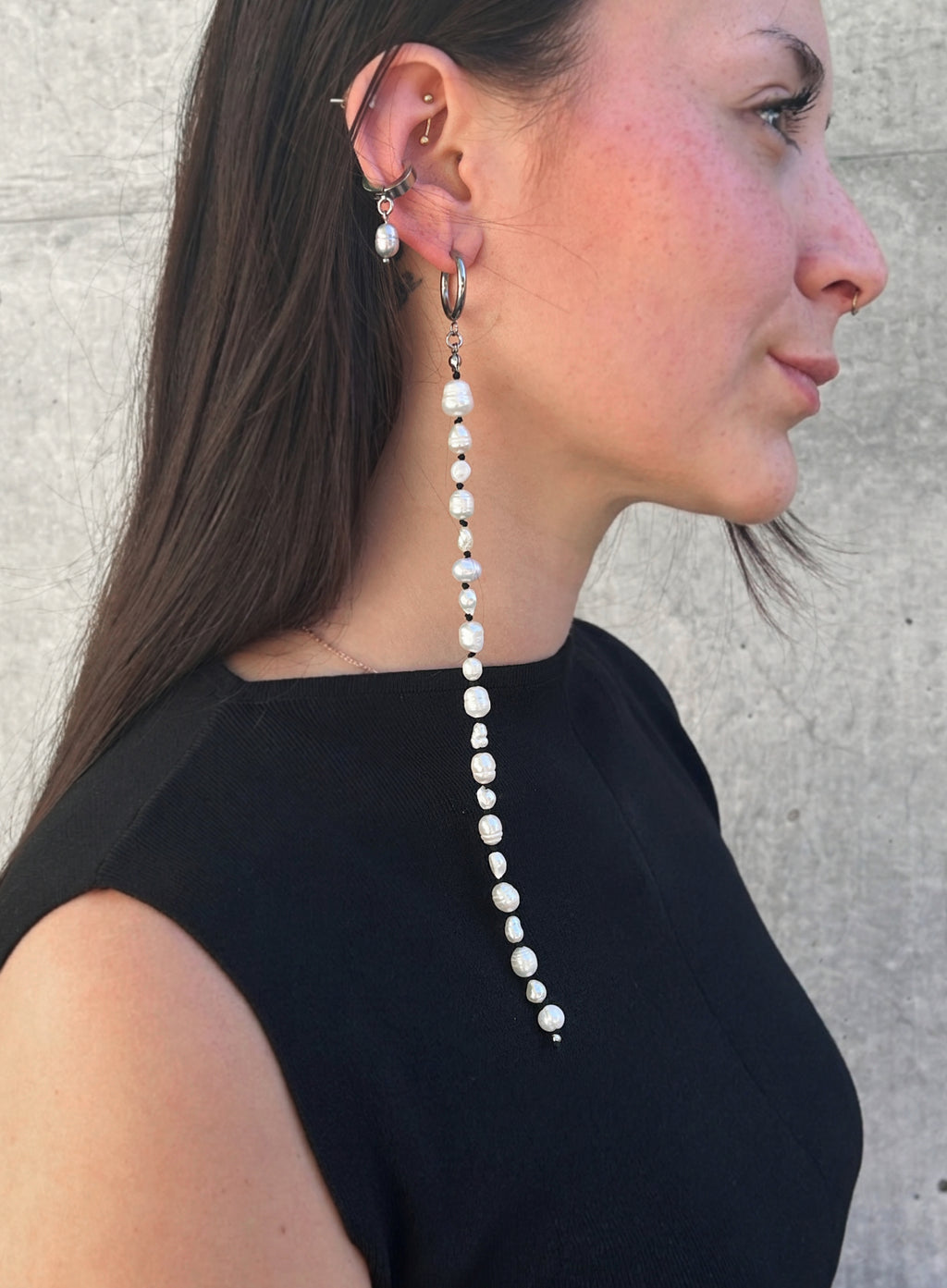 woman in black dress wearing a long shoulder duster pearl earrings and earcuff